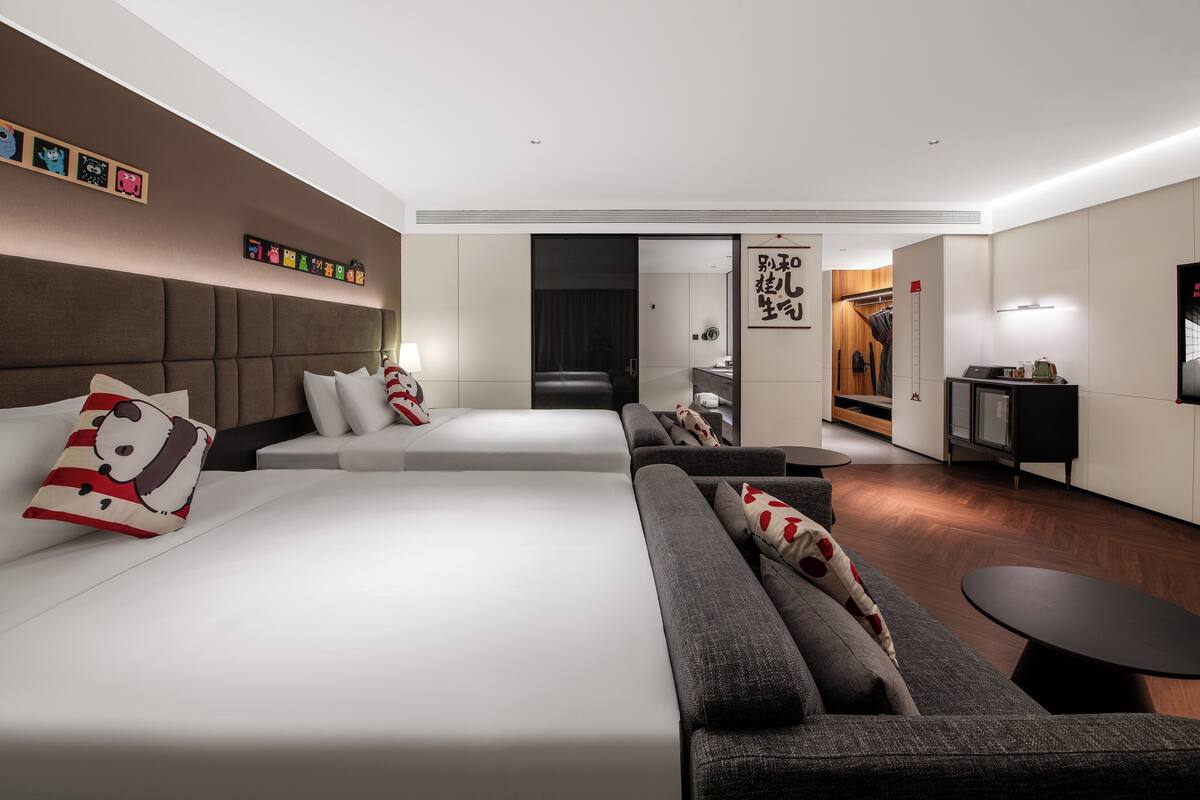 A modern hotel room with a large bed, a sofa, a small table, and a TV.