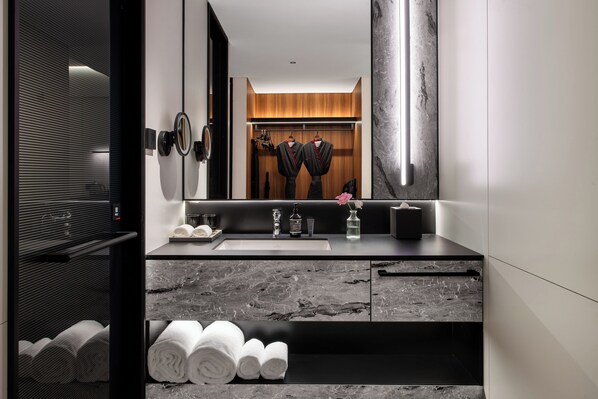 A modern bathroom with a large mirror, a sink, and a towel rack.