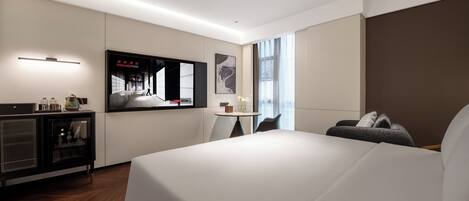 A modern hotel room with a large bed, a small desk, a television, and a window with curtains.