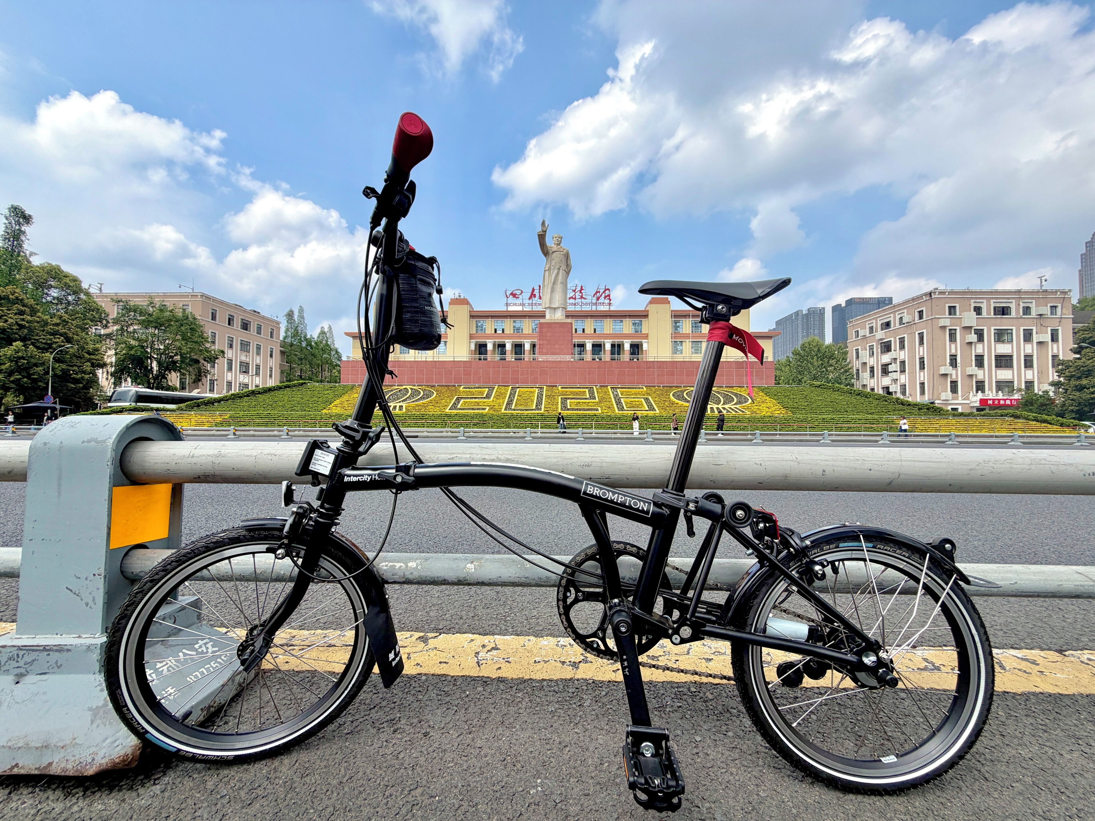 A bicycle parked by a barrier with a cityscape in the background.
