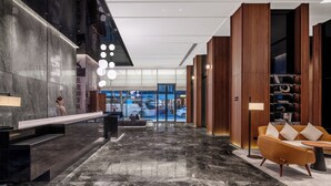 Un vestíbul modern amb taulell de recepció, zona de seients i vista al carrer.