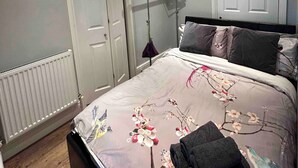 Une chambre à coucher avec un lit, deux portes, un radiateur et un luminaire suspendu.