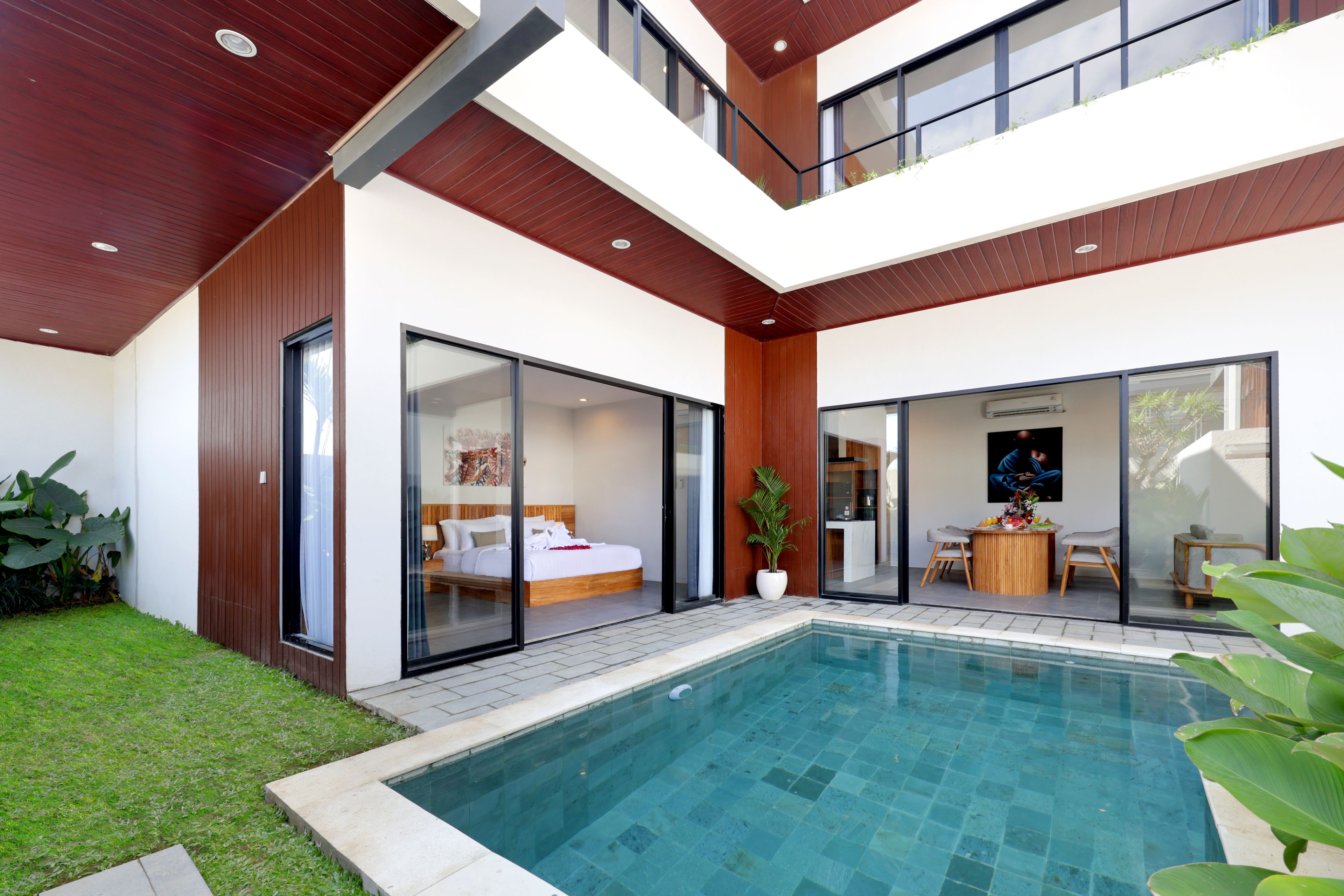 A modern two-story house with a swimming pool, large sliding glass doors, and a dining area.