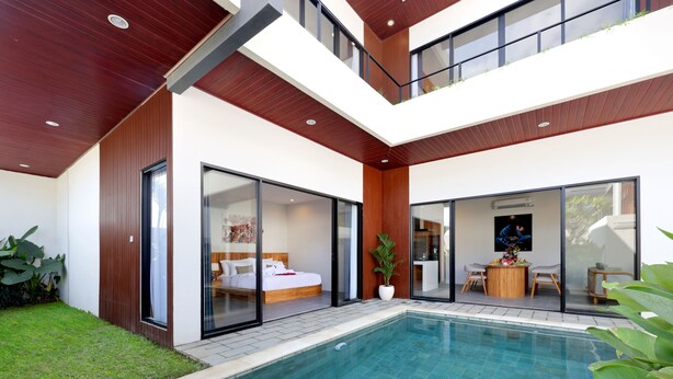A modern two-story house with a swimming pool, large sliding glass doors, and a dining area. - Beachside Luxury 3BR Tropical B (Denpasar)