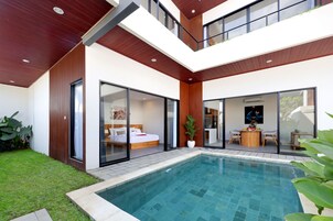 Una casa moderna de dos plantas con piscina, puertas correderas de vidrio grandes y un comedor.