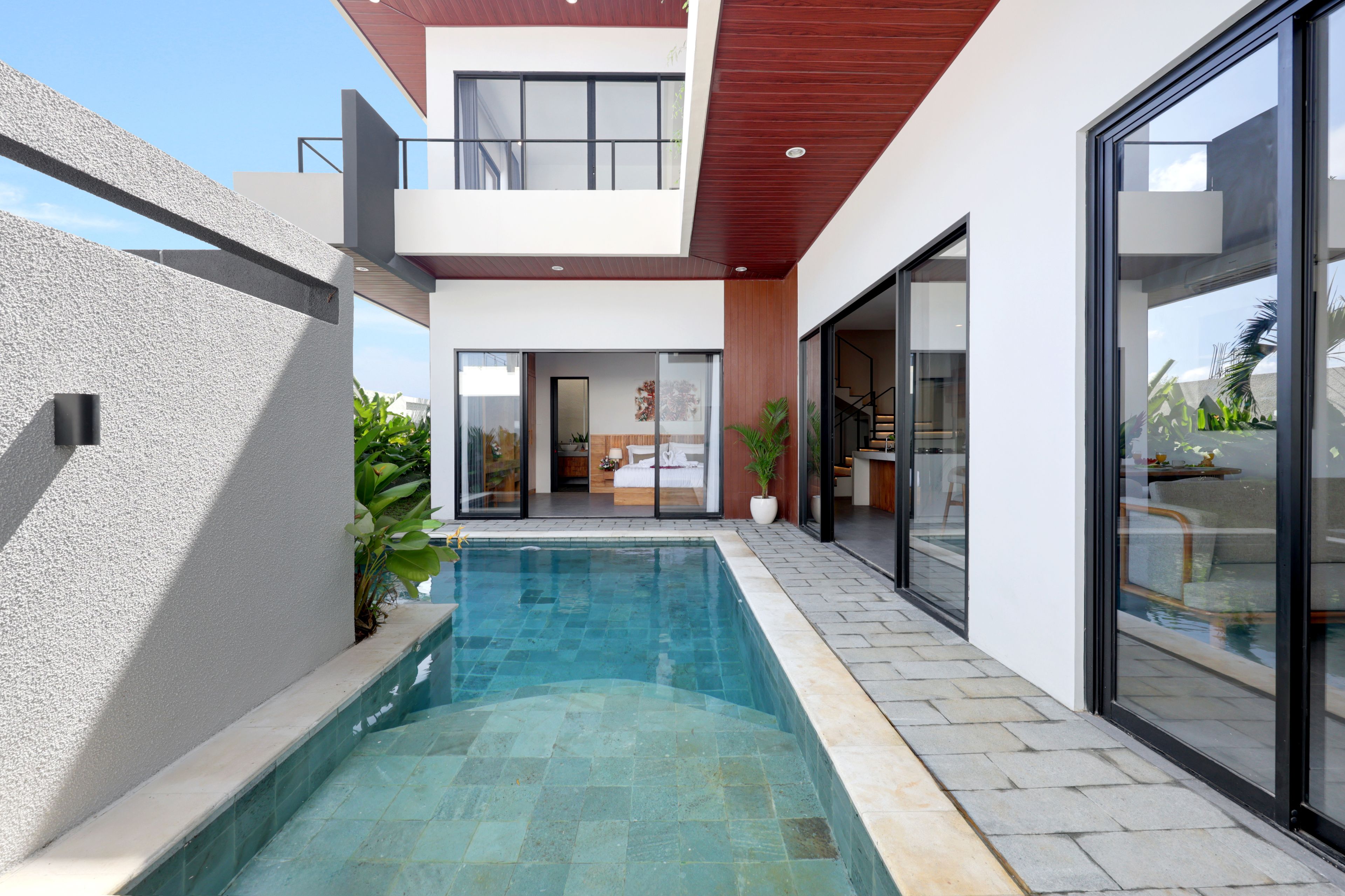 Een modern huis met een zwembad, een balkon en een grote schuifpui.