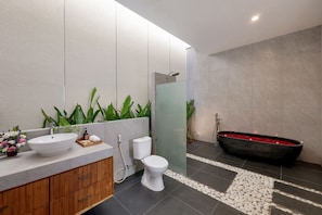 A modern bathroom with a large white sink, a toilet, and a black bathtub. - Beachside Luxury 3BR Tropical B (Denpasar)