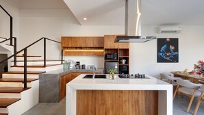 A modern kitchen with a central island, wooden cabinetry, and a built-in microwave. - Beachside Luxury 3BR Tropical B (Denpasar)