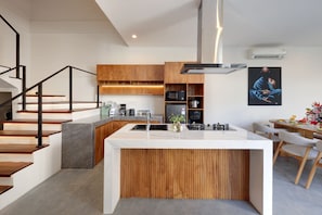 A modern kitchen with a central island, wooden cabinetry, and a built-in microwave. - Beachside Luxury 3BR Tropical B (Denpasar)