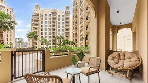 A balcony with wicker chairs, a round cushioned chair, and a small table. - StayShort - Modern 1BR Retreat in MJL Sleeps 4 (Madinat Jumeirah Living)