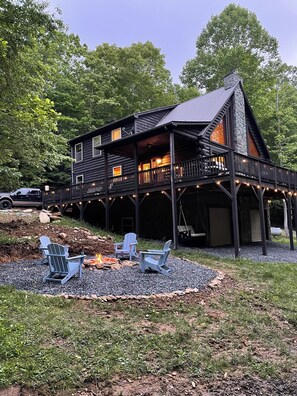 Een lodge met een veranda, zitplaatsen buiten en een vuurkuil.