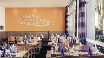 A restaurant with tables set for dining, a large window, and a wall with a geometric design.