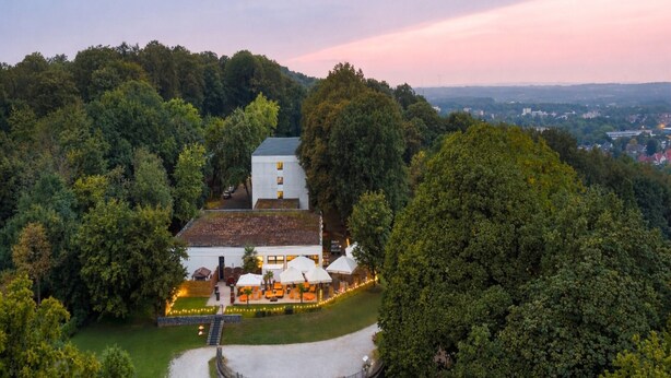 A large building surrounded by lush greenery, with a circular outdoor seating area and a staircase leading to the entrance. - Sunday Hotel Bielefeld Superior King Room (Bielefeld)