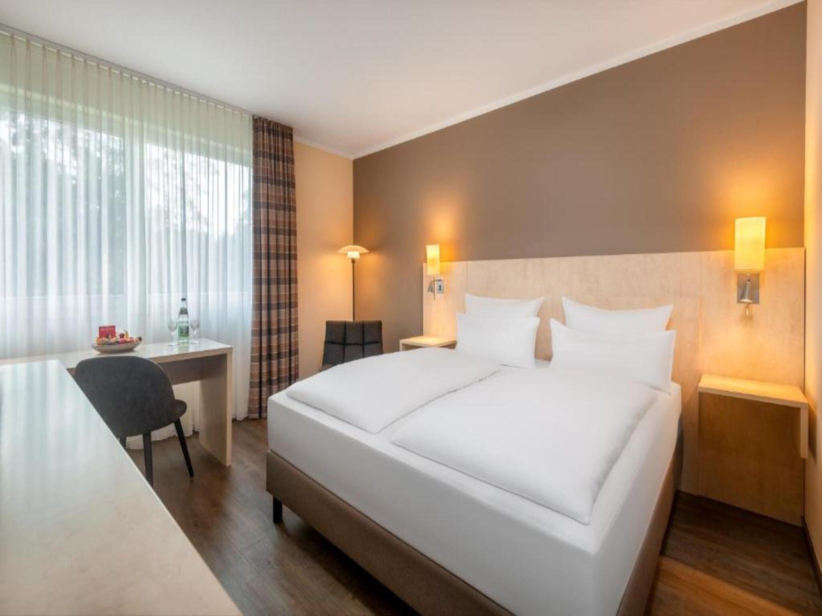 Une chambre d’hôtel comprenant un lit, des tables de chevet, un bureau, une chaise et une lampe.