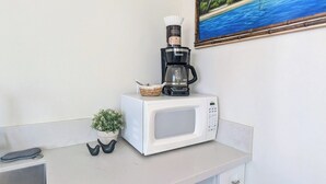 Una kitchenette con microondas, cafetera y una pequeña planta en maceta.