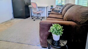Un espacio habitable compacto con kitchenette, un sofá, un escritorio y una silla.