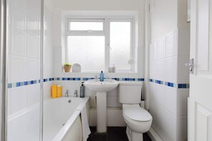 A compact bathroom with a bathtub, sink, toilet, and a window. - Peaceful 2BDR Flat in Serene Clapham Cul de Sac (London)