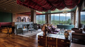 Amplia sala de estar con chimenea, asientos y vistas al exterior.