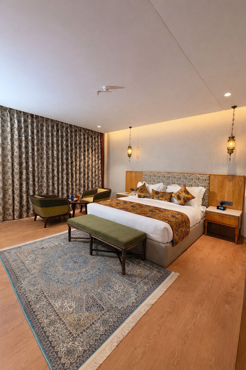 A modern bedroom with a large bed, a bench, a nightstand, a chair, and a patterned rug.