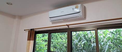 Una habitación con un ventanal grande, un equipo de aire acondicionado y una lámpara en el techo.