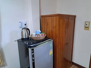 Un kitchenette pequeño con refrigerador, hervidor y una cesta de bocadillos.