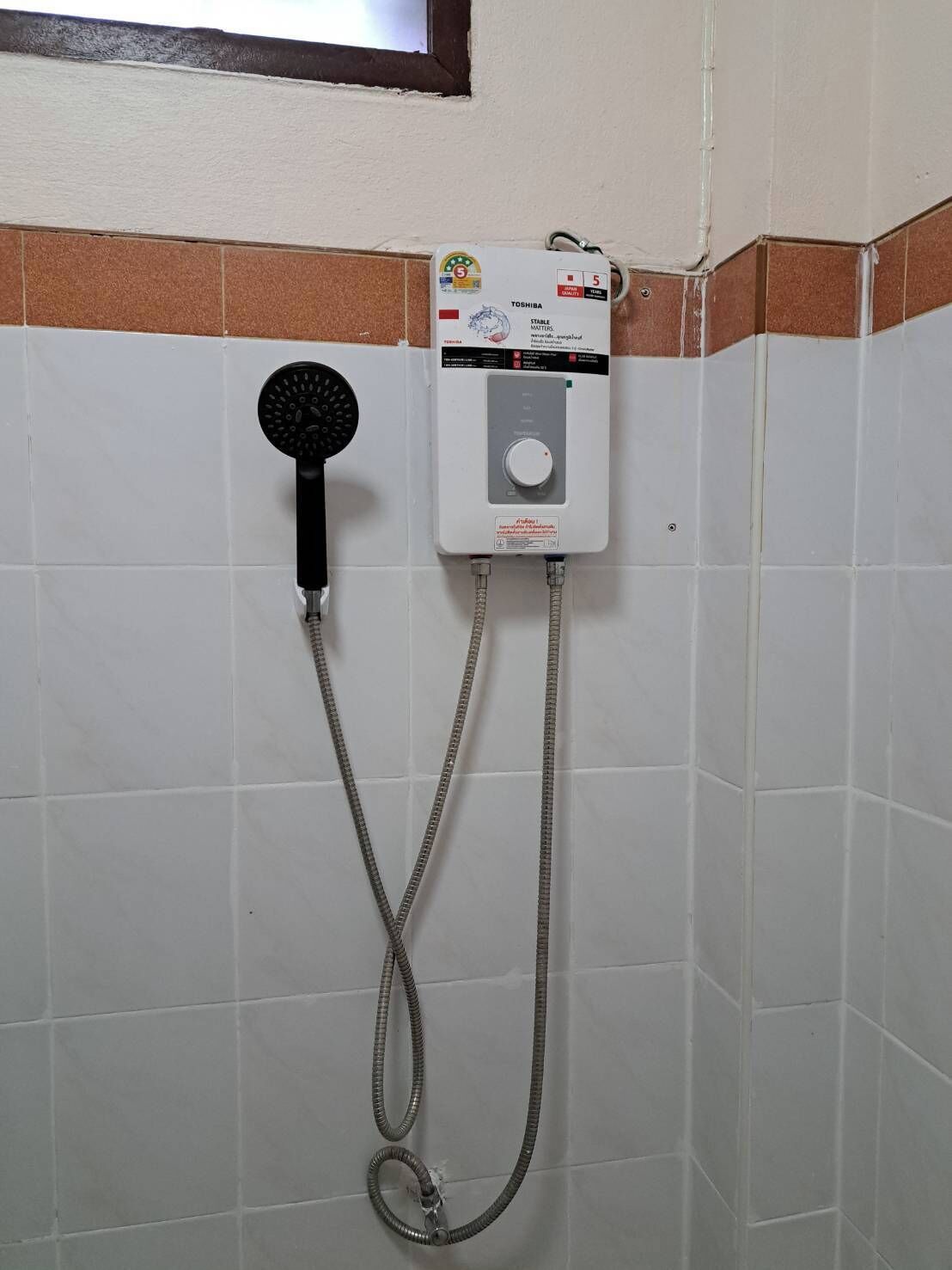 A shower with a handheld showerhead and a wall-mounted control panel.