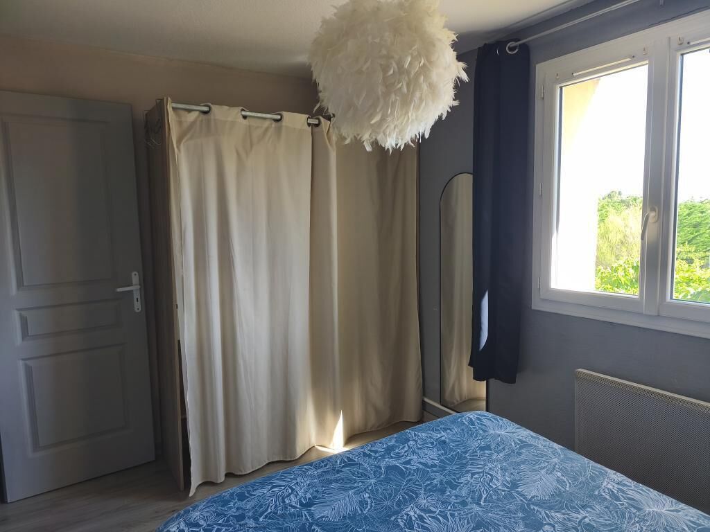 Un dormitorio con cama, cortinas, espejo y ventana.