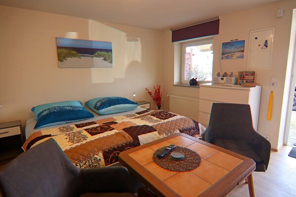 Une chambre à coucher avec un lit, deux chaises, une table avec une télécommande et une fenêtre donnant sur un beau paysage.