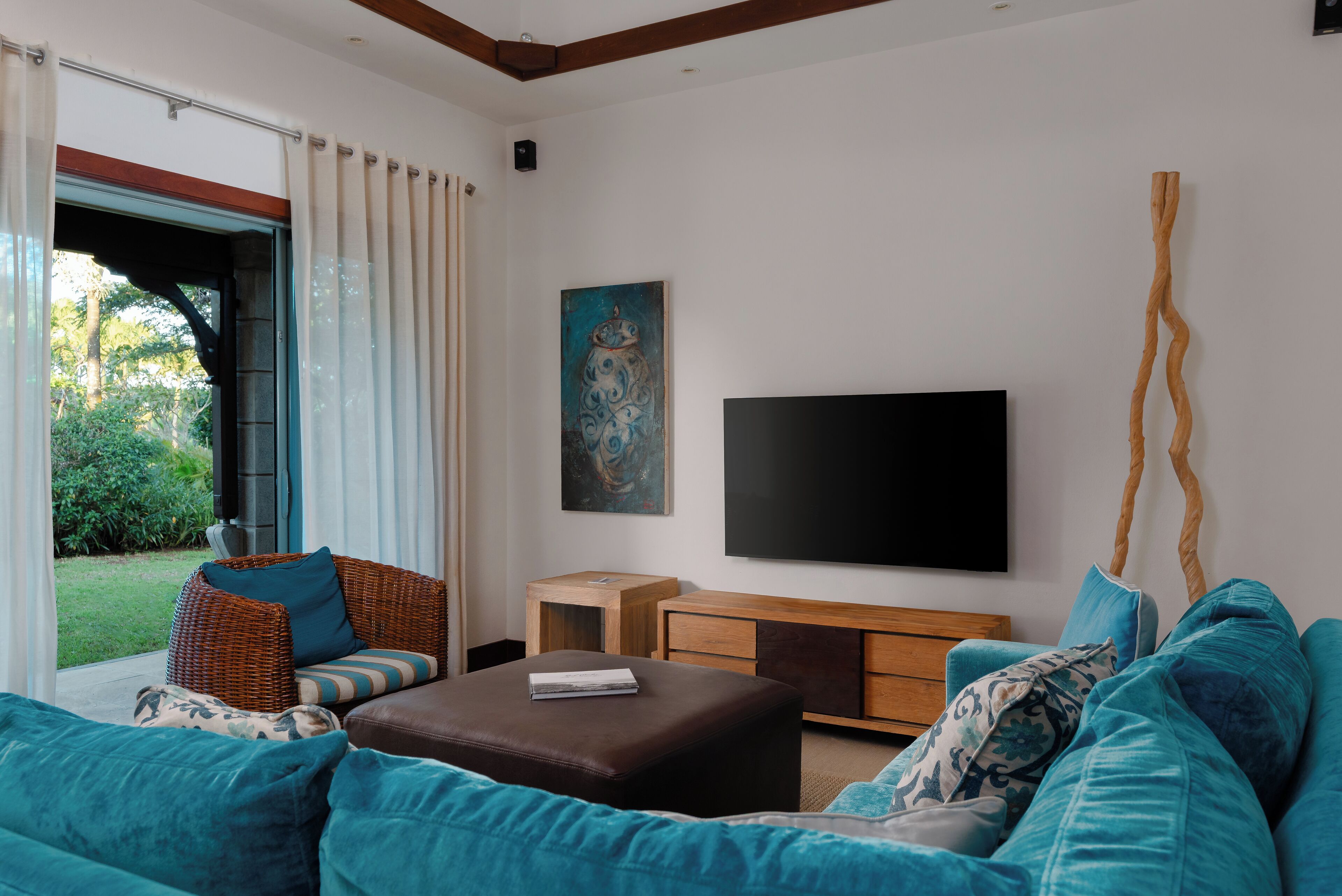 A living room with a sofa, ottoman, and a flat-screen TV mounted on the wall.