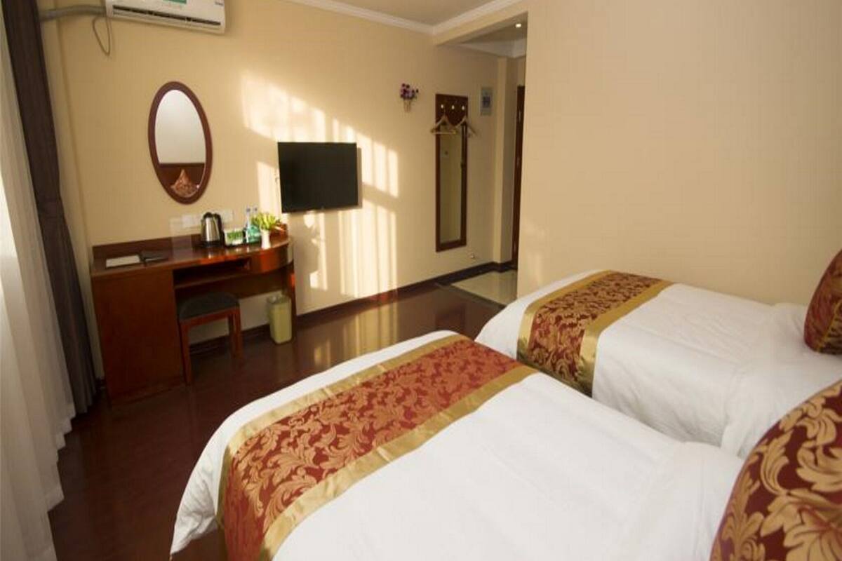 Une chambre d’hôtel avec deux lits, un bureau, un miroir, une télévision et un appareil de climatisation.
