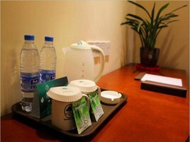 A tray with bottled water, a teapot, and tea packets on a hotel table.