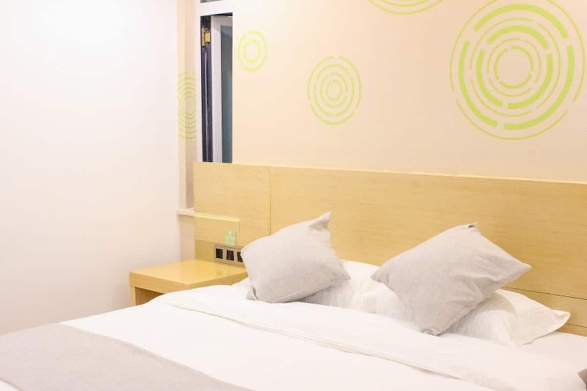 A hotel room with a bed, pillows, a nightstand, and a wall with circular patterns.