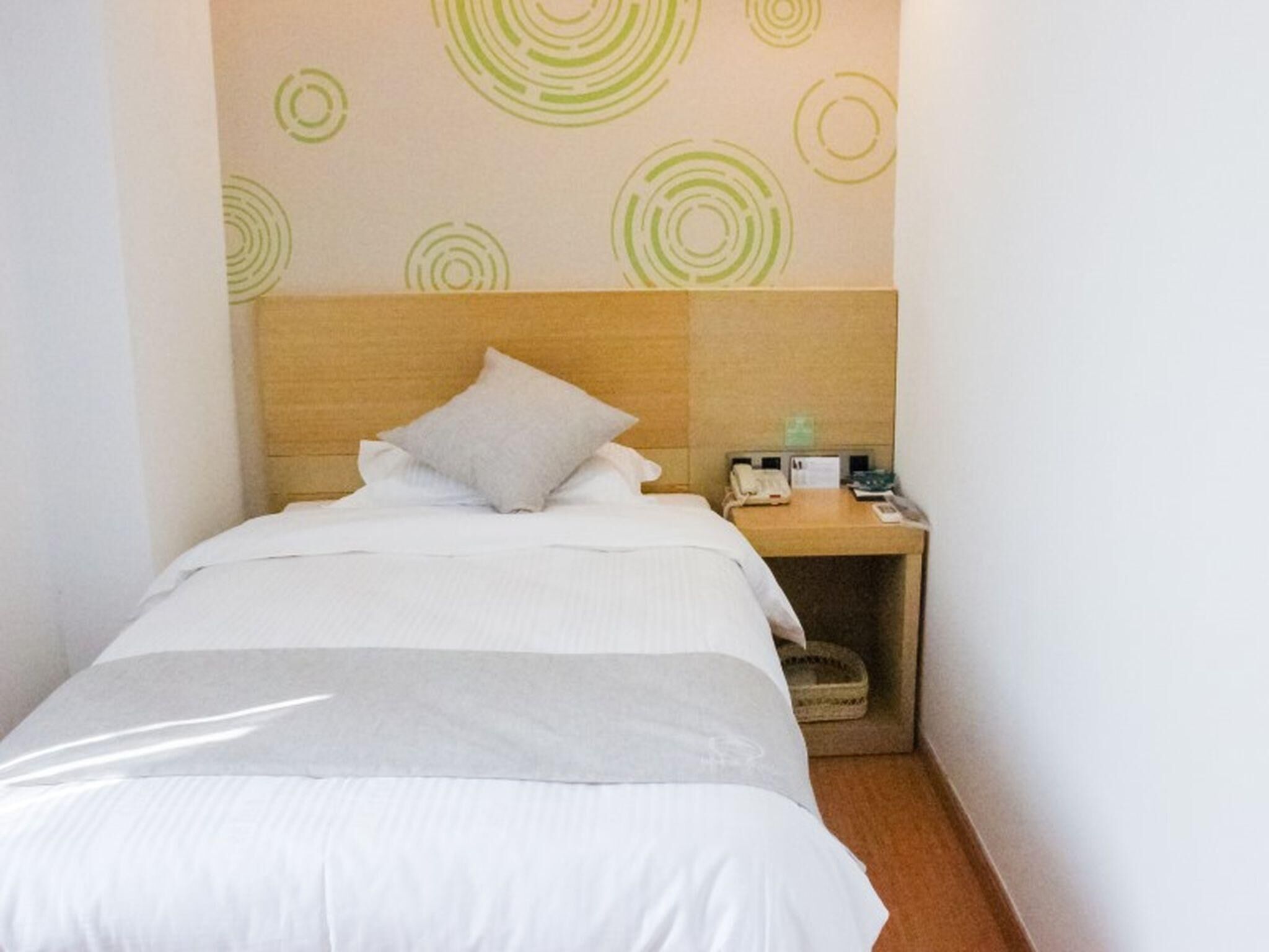 Habitación de hotel con una cama, una mesita de noche y una pared con diseños circulares.