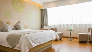 A hotel room with a large bed, a small table with chairs, and a window with curtains. - Greentree Inn (Huai'an)
