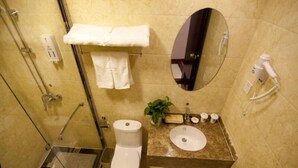 A bathroom with a glass shower enclosure, a toilet, a sink with a mirror above it, and a towel rack with a towel.