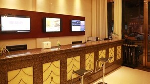 A reception area with a marble counter, three bar stools, and three flat-screen TVs mounted on the wall.