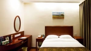 Habitación de hotel con cama, escritorio, teléfono, cesto de basura y un cuadro en la pared.