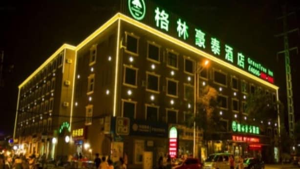 Un hotel de varios pisos con un letrero verde que indica que es un hotel.