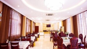Un comedor de hotel con mesas redondas, sillas y una araña.