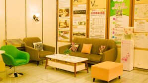 A reception area with a sofa, chairs, a coffee table, and informational posters on the walls.