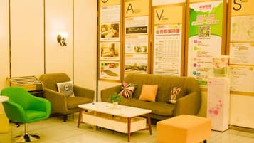 A reception area with a sofa, chairs, a coffee table, and informational posters on the walls.