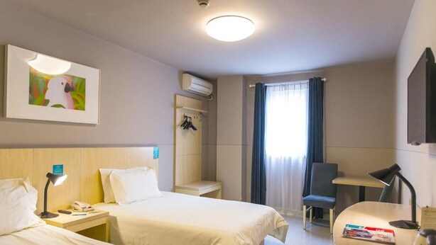 A hotel room with two beds, a desk, a chair, an air conditioning unit, and a window with curtains. - Jinjiang Inn Wuhan Jiangtan Nanjing Road Science Museum (Wuhan)