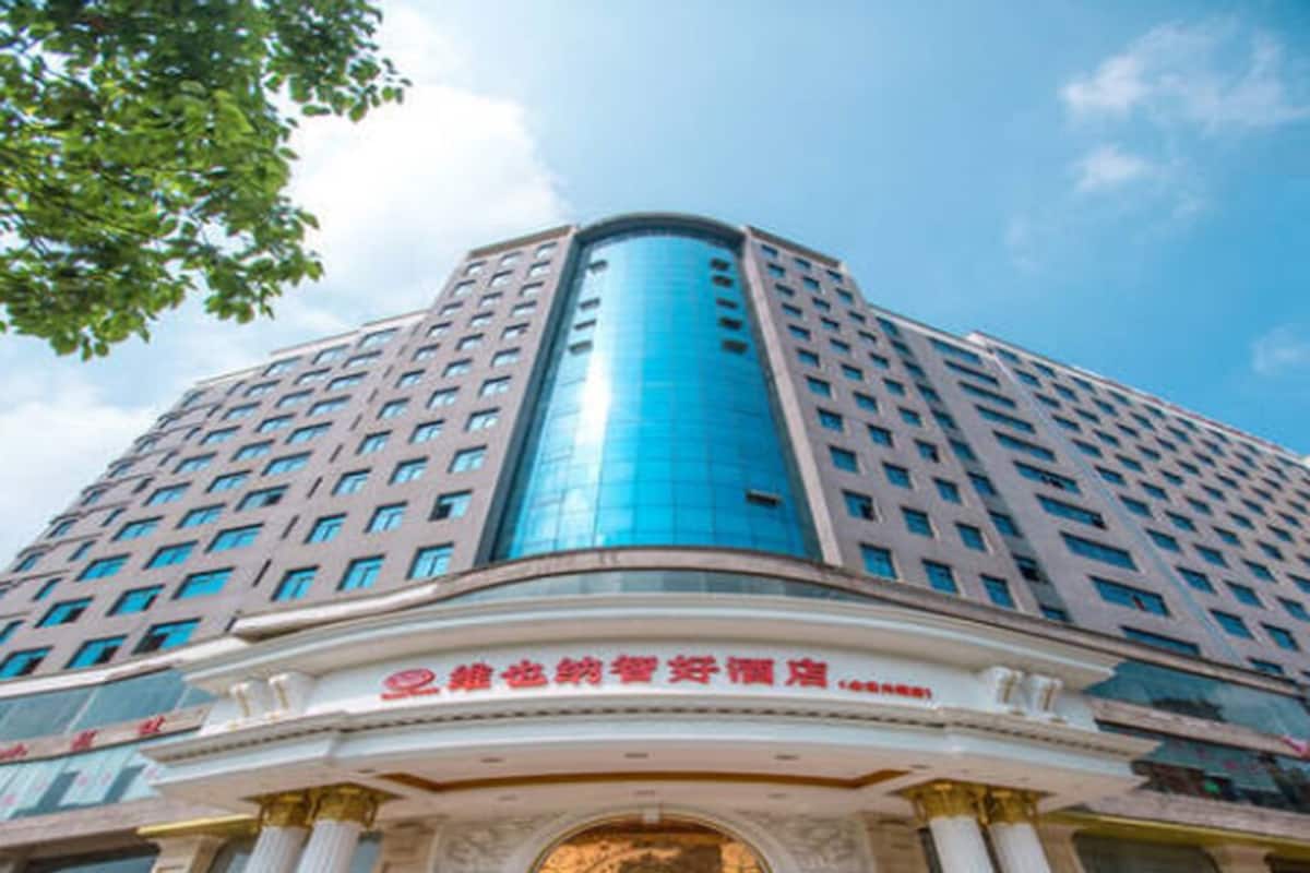 A multi-story building with a curved glass facade and a classical entrance with columns.