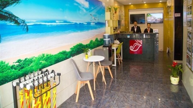 A hotel lobby with a beach mural, a reception desk, and a seating area.