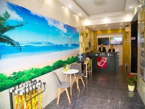 A hotel lobby with a beach mural, a reception desk, and a seating area. - Shell Hotel (Shanghai)