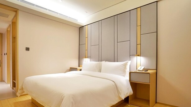 A modern bedroom with a large bed, bedside tables, and a built-in headboard. - JI Hotel Shanghai Baoshan Youyi Road Branch (Shanghai)