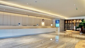 A modern reception area with a marble floor, a reception desk, a digital screen, and a decorative plant. - JI Hotel Shanghai Baoshan Youyi Road Branch (Shanghai)