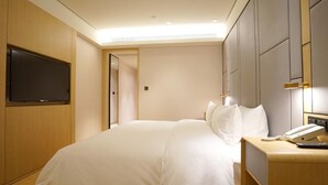 A hotel room with a bed, bedside table with a phone, and a TV mounted on the wall. - JI Hotel Shanghai Baoshan Youyi Road Branch (Shanghai)