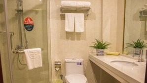 A bathroom with a glass-enclosed shower, a toilet, a sink, and a mirror. - Greentree (Suzhou)