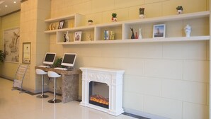 A reception area with a fireplace, two computer monitors, and shelves with decorative items. - Greentree (Suzhou)